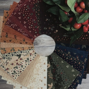 May include: A circular arrangement of fabric squares in a variety of patterns and colours. The fabrics display floral and geometric designs in shades of red, brown, green, and cream. A sprig of red berries and green leaves is in the background.