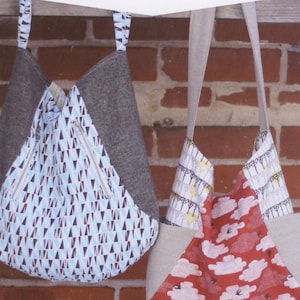 May include: Two tote bags with different patterns hang against a brick wall. One bag has a blue and white geometric pattern, the other has a red cloud pattern. Both have gray accents and long straps. The text "241 TOTE" is at the top.