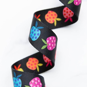 Peut inclure: Un ruban noir orné d'un motif répétitif de pommes stylisées aux couleurs vives, notamment bleu, rose, orange et rouge. Chaque graphique de pomme comprend de petits points et des feuilles vertes, disposés dans un design fluide et sinueux.