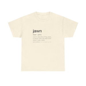 Może przedstawiać: Kremowa koszulka z czarnym napisem "jawn" i jego definicją. Definicja wyjaśnia, że "jawn" jest używane do opisywania rzeczy, miejsca lub osoby, gdy dokładne słowo nie ma znaczenia.