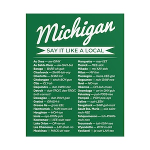 May include: A green rectangular sign with the word "Michigan" in a cursive font. Below, the text "SAY IT LIKE A LOCAL" is in a white font. The sign lists the pronunciation of various Michigan place names.