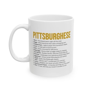 May include: White ceramic mug with a curved handle. The mug features the word "PITTSBURGHESE" in gold lettering, along with a list of definitions. The mug is a humorous gift idea.