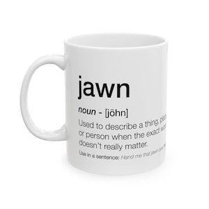 May include: White ceramic coffee mug with the word "jawn" in bold black letters. The mug also includes a definition of the word "jawn" and an example sentence. A simple, everyday mug.