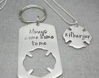 May include: A silver-colored keychain and necklace set. The keychain is a dog tag shape with the words "Always come home to me" and a firefighter emblem cutout. The necklace has a pendant with the name "kilbarger" and a firefighter emblem.