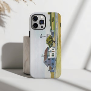 May include: A white iPhone case with a watercolor painting of a farmhouse with a windmill in a field. The case has a camera cutout and a black border.