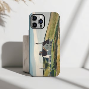 Könnte beinhalten: Eine Handyhülle mit einem Aquarellbild eines weißen Hauses mit schwarzem Dach und einem Leuchtturm in der Ferne. Das Haus steht auf einem grasbewachsenen Hügel mit blauem Himmel und weißen Wolken im Hintergrund.