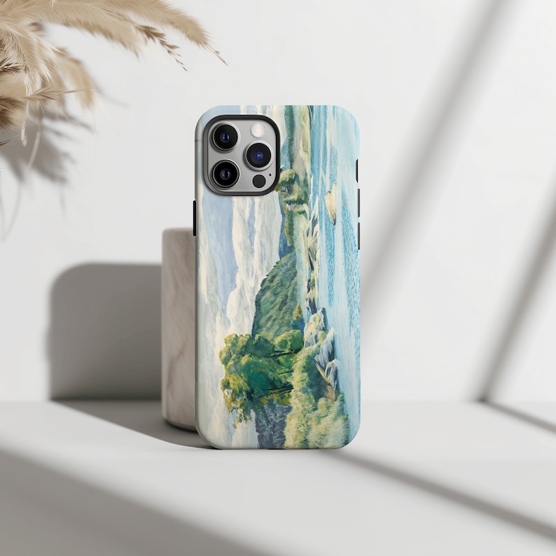 May include: A phone case with a watercolor painting of a landscape with a river and trees. The case is white with a black border and has a camera cutout.