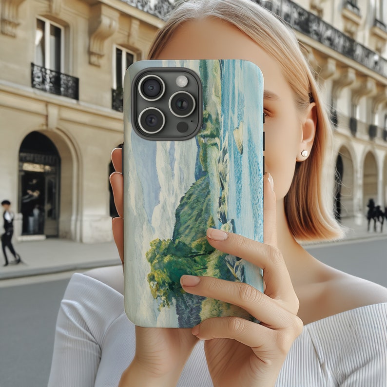 May include: A phone case with a watercolor painting of a landscape with a body of water and trees. The case is designed for a phone with a triple lens camera.