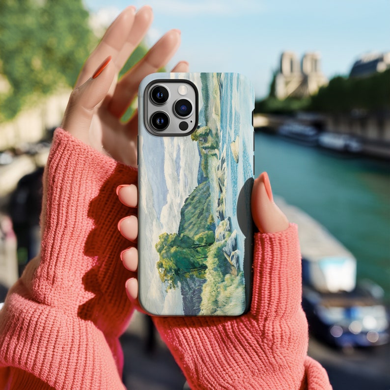 May include: A phone case with a scenic landscape painting of a river and trees. The case has a camera lens cutout and a white background.