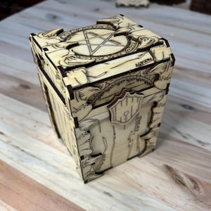 May include: A wooden card box with a decorative design featuring a pentagram and floral motifs. The box has a hinged lid and a keyhole.