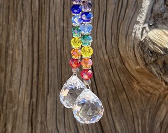 May include: A rainbow crystal suncatcher with clear crystal drops hanging from a silver chain. The suncatcher features a variety of colored beads, including purple, blue, green, yellow, orange, and red.