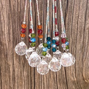 May include: Seven crystal suncatchers with clear faceted balls and beaded strings in various colors, including red, orange, green, blue, and pink.