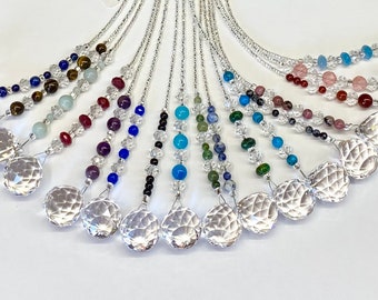 May include: A collection of crystal suncatchers with various gemstone beads. The suncatchers are made of clear crystal and have a faceted design. The beads are in a variety of colors, including blue, green, red, and brown.