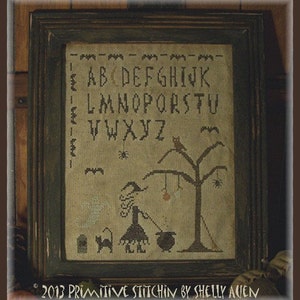 May include: A cross-stitch pattern featuring a witch, a black cat, a ghost, a cauldron, and a tree with bats and spiders. The alphabet is stitched at the top of the pattern. The text at the bottom reads "2013 Primitive Stitchin by Shelly Aven".