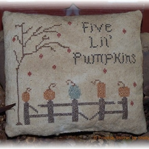 May include: A beige pillow with a cross-stitch design of a tree with five pumpkins and the text "Five Lil' Pumpkins".