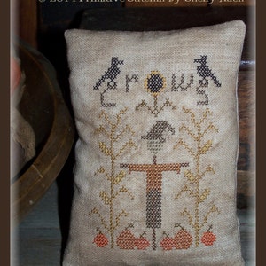 May include: A brown burlap pillow with a cross-stitch design featuring a scarecrow, crows, pumpkins, and the word "Crows".