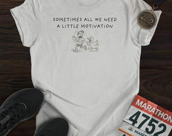 May include: A light grey t-shirt with the text "SOMETIMES ALL WE NEED A LITTLE MOTIVATION" and a cartoon of a runner and a duck. Includes a marathon medal and running shoes.