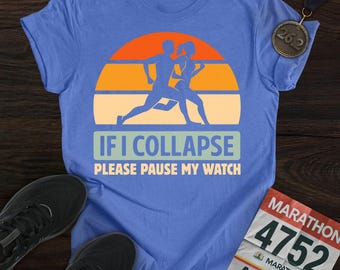 May include: A blue t-shirt with a running couple silhouette design over a sunset graphic. The text reads "IF I COLLAPSE PLEASE PAUSE MY WATCH". Black running shoes, a marathon medal, and a race bib are also visible.