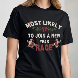 Könnte beinhalten: Schwarzes T-Shirt mit dem Text "MOST LIKELY TO JOIN A NEW YEAR RACE" in Weiß und Rot. Das Design beinhaltet Santa Claus Illustrationen und festliche Akzente.