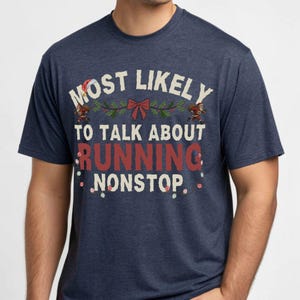 May include: Navy blue t-shirt with the text "MOST LIKELY TO TALK ABOUT RUNNING NONSTOP." The text is in white and red, with festive holiday accents. The shirt is a crew neck and has short sleeves.