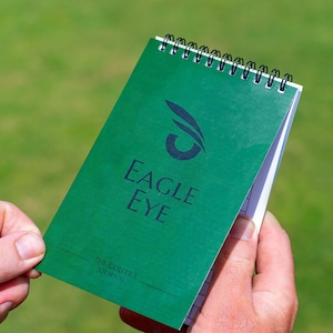 May include: A green spiral bound notebook with the text "Eagle Eye" and "The Golfer's Journal" on the cover.