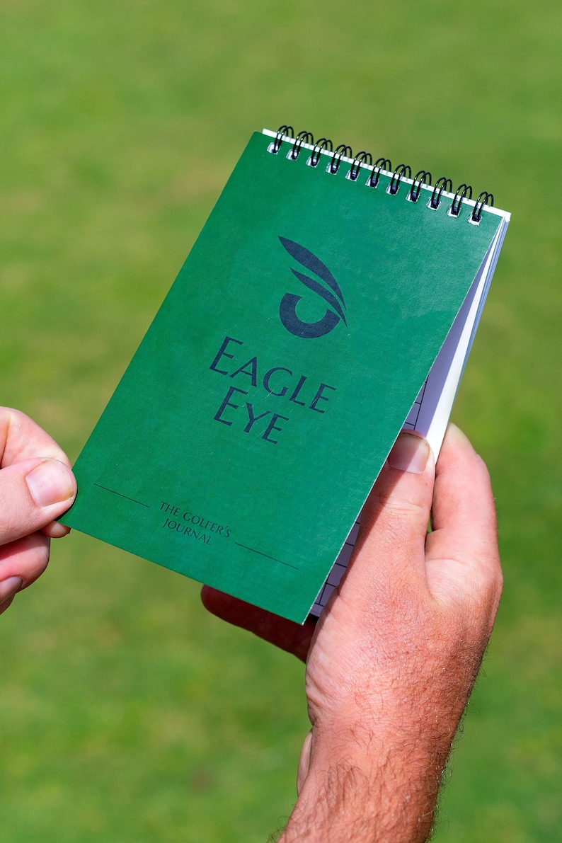 May include: A green spiral bound notebook with the text "Eagle Eye" and "The Golfer's Journal" on the cover.
