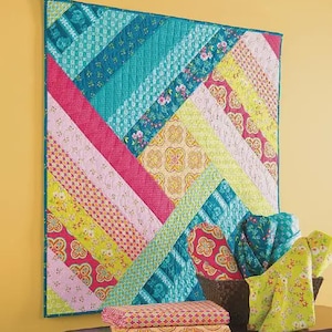 May include: A colorful quilt with a geometric design, featuring diagonal stripes in teal, pink, yellow, and floral patterns. The quilt is displayed on a wall, with folded fabric and baskets in the foreground. The quilt is approximately 48 inches by 48 inches.