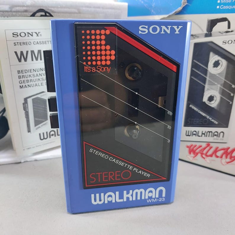 May include: A blue Sony Walkman WM-23 stereo cassette player featuring a black front panel with red accents, the text "It's a Sony" with a dotted logo, "STEREO CASSETTE PLAYER", and "WALKMAN WM-23" printed in white on the blue plastic casing.