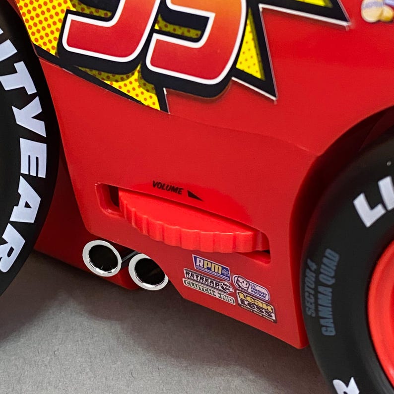May include: A red toy car with a volume knob, two exhaust pipes, and various stickers including "RPM", "RATBEAR'S", "GAMMA QUAD", and "SECTOR 4".