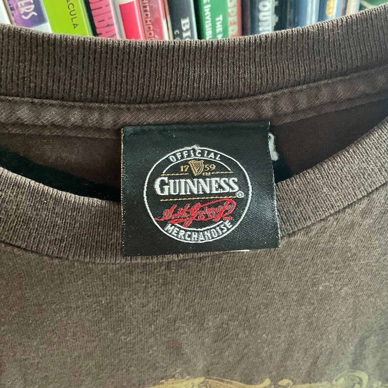 May include: A black tag with white text that reads "Official Guinness Merchandise" with a Guinness logo and the year 1759.