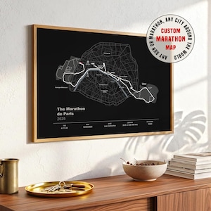 Könnte beinhalten: Ein gerahmter Schwarz-Weiß-Plan der Marathonstrecke von Paris. Die Karte enthält den Text "The Marathon de Paris 2025". Ein kreisförmiges Grafik-Element zeigt "Custom Marathon Map, Any City Around The World". Der Rahmen ist aus Holz.