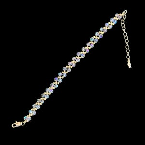 May include: A gold bracelet with a delicate chain and iridescent crystal beads. The bracelet has a lobster clasp closure.