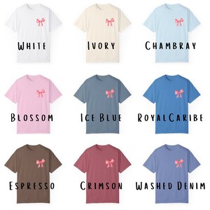 Pode incluir: Nove t-shirts de cores diferentes com um la&ccedil;o rosa na frente. As cores s&atilde;o branco, marfim, Chambray, flor, azul gelo, azul real, espresso, carmesim e denim lavado.