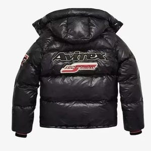 May include: Black puffer jacket with a hood. The jacket features the brand name "Avirex" in white and red lettering on the back, along with a patch. The jacket has a glossy finish and a quilted design.