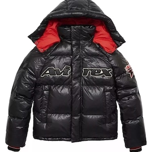 May include: A black puffer jacket with a hood and red lining. The jacket features the text "Avirex" in white across the chest and a patch on the sleeve. The jacket has a shiny, quilted appearance.