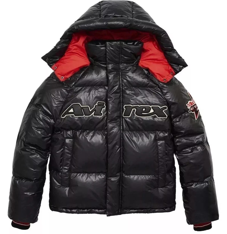 May include: A black puffer jacket with a hood and red lining. The jacket features the text "Avirex" in white across the chest and a patch on the sleeve. The jacket has a shiny, quilted appearance.