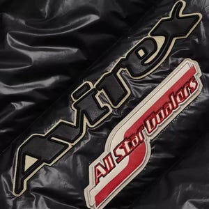 May include: Black jacket with two embroidered patches. One patch reads "AVIREX" in black letters with a cream border. The second patch says "All Star Coolers" in red and white.