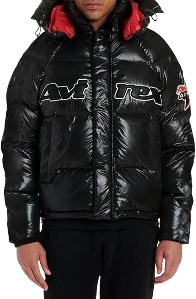 May include: Black puffer jacket with a red-lined hood. The jacket features the white text "Avirex" across the chest. A small logo is on the right sleeve. The jacket has a shiny, quilted appearance.