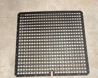 May include: Black metal grid panel with a rectangular shape and a small rectangular cutout in the bottom center. The grid is made up of small squares.