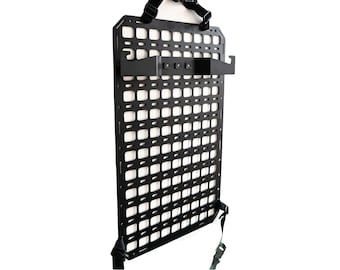 May include: Black metal wall-mounted grid panel with straps and a hook. The panel has a grid pattern with many small squares.