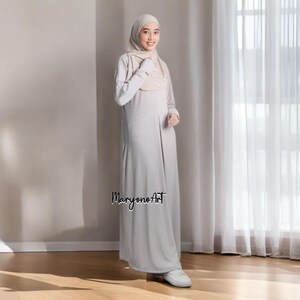 May include: A light gray maxi dress with long sleeves and a matching head covering. The dress has a simple, elegant design and is paired with white sneakers. The text "MaryonoArt" is visible on the lower part of the dress.