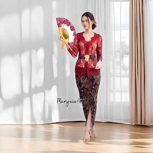 Op de afbeelding: Een vrouw draagt een rood kanten topje met een zwarte riem en een zwarte rok met rood patroon. Ze houdt een rode en witte handwaaier vast.