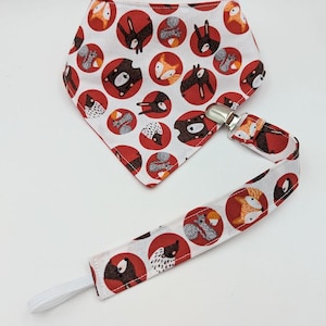 May include: A white bandana with a red and white pattern of woodland animals, including foxes, bears, squirrels, and hedgehogs. The bandana has a white elastic strap with a clip attached.