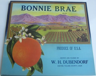 Puede incluir: Etiqueta de caja de naranjas vintage de la marca Bonnie Brae. La etiqueta presenta una naranja con flores, un paisaje de campos y montañas, y el texto "Produce of U.S.A." y "Grown and Packed by W. H. Dubendorf."