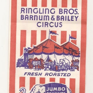 May include: A red and white striped paper bag with the text "Ringling Bros. Barnum & Bailey Circus" printed in purple. The bag also features an illustration of a circus tent and a cartoon elephant wearing a sign that says "Jumbo Peanuts". The text "Fresh Roasted" is printed below the circus tent.