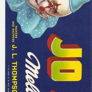 May include: Vintage fruit crate label featuring a smiling clown's face with red accents, a blue polka-dot collar, and a blue hat. The label reads "JO JO" in large, colorful letters, and "Melons" in cursive. The label also includes the text "Produce of U.S.A."