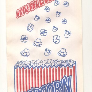 May include: A white paper bag with red and blue stripes at the bottom. The bag has the words "HOT & DELICIOUS" printed in red and "POPCORN" printed in blue. The bag is decorated with blue popcorn kernels.
