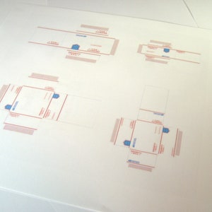 Peut inclure: Un mod&egrave;le de bo&icirc;te &agrave; plat pour une bo&icirc;te Priority Mail. Le mod&egrave;le est imprim&eacute; sur du papier blanc avec des lignes rouges et bleues. Le mod&egrave;le comprend le texte "Priority Mail" et "USPS" en bleu.