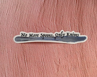 以下が含まれることがあります： 青いナイフのイラストと「No More Spoons, Only Knives」という黒い筆記体で書かれたテキストが描かれた白いステッカーです。