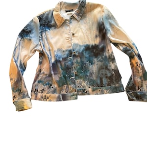 Peut inclure: Une chemise à manches longues à boutons avec un imprimé abstrait bleu, blanc et marron. La chemise a un col et une fermeture à boutons.